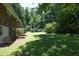 Green backyard with lush lawn, a brick house exterior, and mature trees for a serene outdoor setting at 1964 Wellington Rd, Burlington, NC 27217
