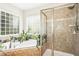 Bright bathroom with tub, tile shower, glass block window, and plants at 203 Pathwood Ln, Durham, NC 27705