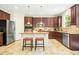 Kitchen featuring dark wood cabinets, stainless appliances, granite counters, and an island with seating at 203 Pathwood Ln, Durham, NC 27705