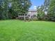 Expansive backyard with a view of the home, screened-in porch and mature trees at 218 Inwood Forest Dr, Raleigh, NC 27603