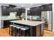 Kitchen with black cabinets, stainless steel refrigerator and an island with seating at 218 Inwood Forest Dr, Raleigh, NC 27603