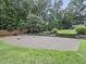 Backyard tennis court with basketball hoop surrounded by lush lawn and mature trees at 218 Inwood Forest Dr, Raleigh, NC 27603