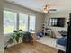 Bright living room area with large windows, TV, a ceiling fan, hardwood floors and ample space at 223 Chauncey Cir, Chapel Hill, NC 27516