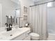 Clean bathroom featuring a shower-tub combo with black and white shower curtain, toilet, and vanity with modern fixtures at 2413 Whelen Dr, Graham, NC 27253