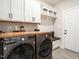Well-equipped laundry room with white cabinets, butcher block countertop, and modern washer/dryer units at 2413 Whelen Dr, Graham, NC 27253
