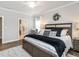 Spacious main bedroom with a wooden bed frame, stylish decor, and a glimpse into the ensuite bathroom at 2413 Whelen Dr, Graham, NC 27253