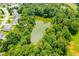 An aerial view showcases a serene pond surrounded by lush greenery and mature trees at 2419 Pepperstone Dr, Graham, NC 27253