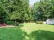 Expansive backyard featuring lush lawn, mature trees, in-ground pool and stone firepit for outdoor relaxation at 334 Dell Meadows Pl, Four Oaks, NC 27524