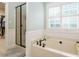 Bright bathroom featuring a soaking tub, separate shower, and classic white shutters at 334 Dell Meadows Pl, Four Oaks, NC 27524