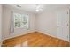 Bedroom with hardwood floors, neutral paint, and natural light from a large window at 3821 Whispering Branch Rd, Raleigh, NC 27613