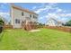A fully fenced backyard showcases a well-maintained lawn and a wooden deck with steps leading to a concrete patio at 410 Stranraer Ct, Fuquay Varina, NC 27526