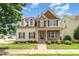 Inviting two-story home featuring stone accents, dormer windows, and a well-manicured front lawn at 410 Stranraer Ct, Fuquay Varina, NC 27526