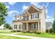 Inviting two-story home featuring stone accents, dormer windows, and a well-manicured front lawn at 410 Stranraer Ct, Fuquay Varina, NC 27526