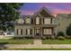 Inviting two-story home featuring stone accents, dormer windows, and a well-manicured front lawn at dusk at 410 Stranraer Ct, Fuquay Varina, NC 27526
