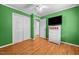 Bedroom with hardwood floors, closet, ceiling fan, and bright green walls at 410 W Tenth St, Siler City, NC 27344