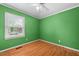 Empty bedroom with hardwood floors, ceiling fan, and bright green walls with natural light at 410 W Tenth St, Siler City, NC 27344