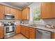 Modern kitchen with stainless steel appliances, granite countertops, wood cabinets and a bright window with backyard view at 4524 Drewbridge Way, Raleigh, NC 27604