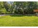 Lush backyard with mature trees, a white fence, and a deck for outdoor enjoyment at 5125 Pinehall Wynd, Raleigh, NC 27604