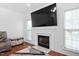 Living area with hardwood floors, a fireplace, a mounted tv, and lots of light from the windows at 5125 Pinehall Wynd, Raleigh, NC 27604