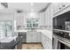 Kitchen with white cabinets, stainless steel appliances, stone backsplash and a view of the backyard at 5125 Pinehall Wynd, Raleigh, NC 27604