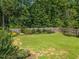 Large, well-maintained backyard with a wooden fence, mature trees, and neatly manicured flowerbeds at 515 Legacy Dr, Youngsville, NC 27596