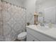 Well-lit bathroom with elegant fixtures, a patterned shower curtain, and decorative accents above the vanity at 515 Legacy Dr, Youngsville, NC 27596