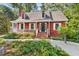 Inviting red home with white trim, a covered porch, and lush landscaping creating curb appeal at 6728 Glen Forrest Dr, Chapel Hill, NC 27517