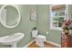 Charming powder room with a pedestal sink, wood flooring, and a decorative mirror at 9 Monteith Ct, Durham, NC 27713