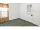 Bright bedroom with neutral walls, green carpet, a window, and a door at 907 Morehead Ave, Durham, NC 27707