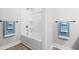 A well-lit bathroom shows a white tub and shower combination, framed by gray walls and matching blue towels at 1004 Snow Peak Ct, Raleigh, NC 27603