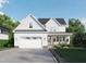 Charming two-story home showcasing a manicured lawn, gray roof, inviting porch, and attached two car garage at 1004 Snow Peak Ct, Raleigh, NC 27603