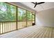 A screened porch with light wood flooring provides a clear view of a lush, green backyard and a dark ceiling fan at 1004 Snow Peak Ct, Raleigh, NC 27603