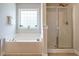 Inviting bathroom featuring a garden tub, glass-enclosed shower, and bright window at 1035 Evening Shade Ave, Rolesville, NC 27571