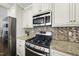 Close up of stainless steel range with microwave, refrigerator and mosaic backsplash at 1123 Ambrose Dr, Rolesville, NC 27571