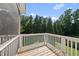 View of a screened-in patio with wood flooring and white railings overlooking lush trees and blue skies at 1123 Ambrose Dr, Rolesville, NC 27571