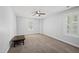 Large bedroom featuring neutral walls, carpeted floor, two bright windows, a ceiling fan, and a dark wood storage shelf at 116 Hidden Cellars Dr, Holly Springs, NC 27540