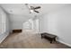 Large, carpeted bonus room with neutral walls, two windows, ceiling fan, and two dark wood storage shelves at 116 Hidden Cellars Dr, Holly Springs, NC 27540