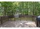 Wooden deck with dark brown stain, black grill, open railing, and a view of the backyard trees at 116 Hidden Cellars Dr, Holly Springs, NC 27540