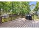 Wooden deck with dark brown stain, black grill, open railing, and a view of the backyard trees at 116 Hidden Cellars Dr, Holly Springs, NC 27540