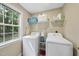 Functional laundry room with a washer, dryer, overhead shelving, and a bright window at 116 Hidden Cellars Dr, Holly Springs, NC 27540