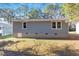 Side view of the home with gray siding, white windows, and a brick foundation at 1203 Freeman Dr, Sanford, NC 27330