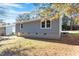 Side view of the gray home, showcasing its brick foundation and natural surroundings at 1203 Freeman Dr, Sanford, NC 27330