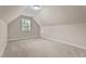An unfinished attic space featuring neutral carpet, a small window and entry doors for easy storage and access at 149 Hadley Ln, Clayton, NC 27527