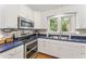 White kitchen with blue countertops, stainless steel appliances, and a garden view at 150 Williamston Ridge Dr, Youngsville, NC 27596