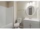 Bright bathroom with modern vanity, round mirror, and tiled shower-tub combo at 1611 Poole Rd, Raleigh, NC 27610