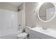 Clean, white bathroom showcasing a round mirror, tiled shower and tub combo, and a sink with vanity at 1611 Poole Rd, Raleigh, NC 27610