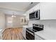 Modern kitchen featuring white cabinets, stainless steel appliances, white countertops, and wood-look flooring at 1611 Poole Rd, Raleigh, NC 27610