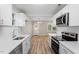 Modern kitchen with white cabinets, stainless steel appliances, white countertops, and wood-look flooring at 1611 Poole Rd, Raleigh, NC 27610