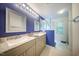 Bathroom featuring double vanity sinks with gray cabinets and a glass enclosed shower at 1909 Piperwood Ct, Durham, NC 27713