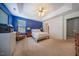 This bedroom features a bed with a floral quilt, blue walls, and a tray ceiling with a fan at 1909 Piperwood Ct, Durham, NC 27713